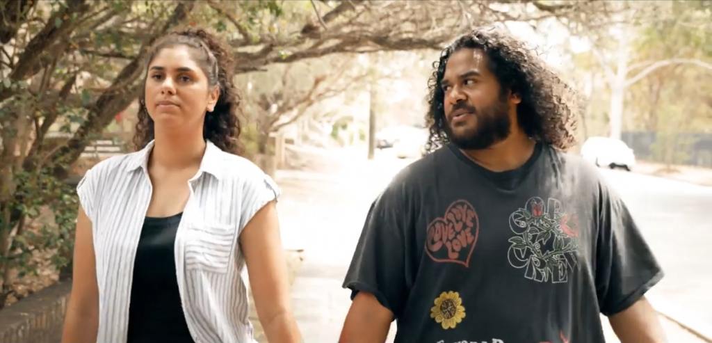 Aboriginal and Torres Strait Islander man and woman talking while walking down the street,